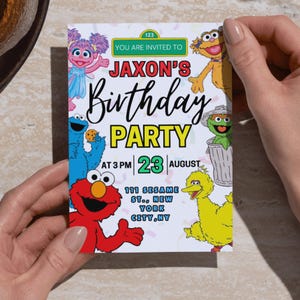 May include: A birthday party invitation featuring Sesame Street characters. The invitation reads "Jaxon's Birthday Party" with the date and time. The invitation is held by a person.