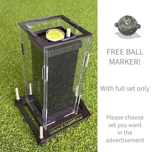 Puede incluir: Una vitrina transparente de acrílico y metal negro con un nivel y una pequeña clavija de madera en el interior. El texto "FREE BALL MARKER! With full set only" es visible. La vitrina está sobre una superficie verde.