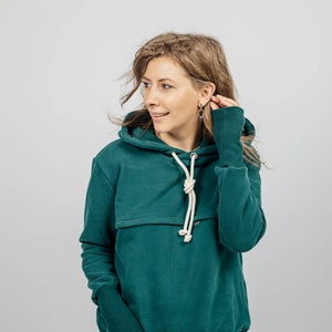 May include: A teal green hoodie with a kangaroo pocket and a white drawstring. The hoodie has a relaxed fit and is made of a soft, comfortable fabric.