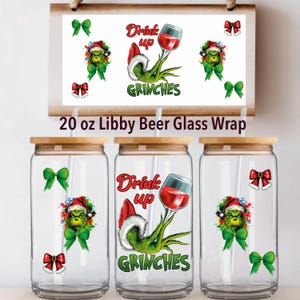 May include: Three clear glass beer can wraps with wooden lids, each featuring a Grinch design with a Santa hat, a wine glass, and the words "Drink Up Grinches." The image also includes green bows and the text "20 oz Libby Beer Glass Wrap."