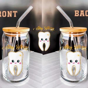 May include: Two clear glass jars with bamboo lids and clear straws. The jars have a white tooth with a pink smile and the text "Stay Flossy" printed on them.