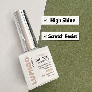 Może przedstawiać: Przezroczysta butelka lakieru do paznokci Lumigo No Wipe Top Coat Protector UV/LED Soak-Off Gel Polish. Butelka jest oznaczona nazwą marki, nazwą produktu i jego cechami, w tym odpornością na zarysowania, dodatkową ochroną i wysokim połyskiem. Butelka zawiera 8 gram&oacute;w.