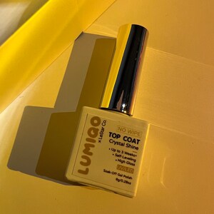 May include: A white bottle of Lumigo x LeStar Co. No Wipe Top Coat Crystal Shine UV/LED Soak-Off Gel Polish. The bottle is labelled with the product name, brand, and instructions for use. It is 8g/0.28oz.