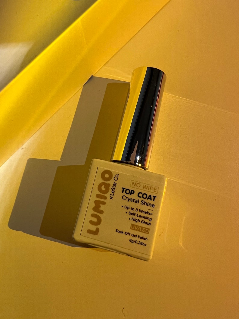 May include: A white bottle of Lumigo x LeStar Co. No Wipe Top Coat Crystal Shine UV/LED Soak-Off Gel Polish. The bottle is labelled with the product name, brand, and instructions for use. It is 8g/0.28oz.