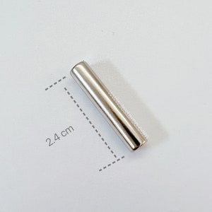 May include: A silver metal rod measuring 2.4 inches in length. The rod is smooth and has a shiny finish.