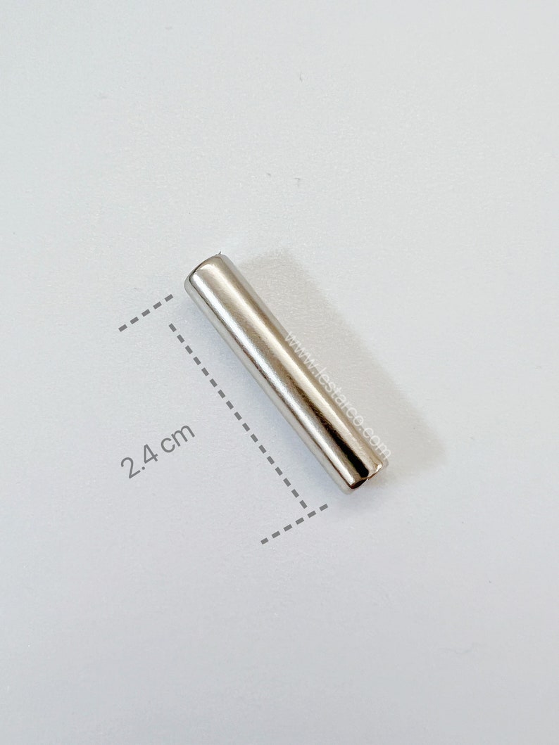 May include: A silver metal rod measuring 2.4 inches in length. The rod is smooth and has a shiny finish.