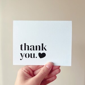 May include: White card with black text that says "thank you." A black heart is next to the text.