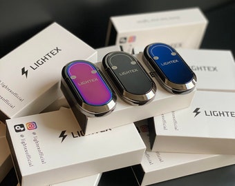 May include: Three small, rectangular, silver-colored lighters with different colored tops. The lighters are on top of white boxes with the word "LIGHTEX" printed on them. The boxes are stacked on top of each other.