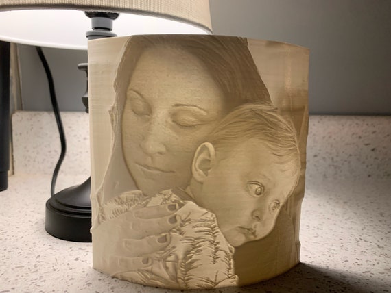 beautiful 3d printed lithophane photo held up to a window with light shining through