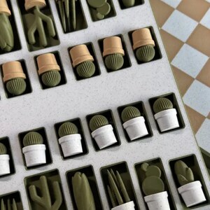 Puede incluir: Un tablero de juego blanco con piezas de juego verdes en forma de cactus. El tablero tiene un patr&oacute;n de cuadr&iacute;cula y est&aacute; dividido en cuadrados. Las piezas de juego est&aacute;n dispuestas en filas y columnas en el tablero.
