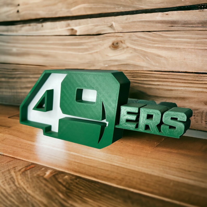 May include: Green and white 3D plastic number 49ers sign. The number 49 is larger than the word "ers".