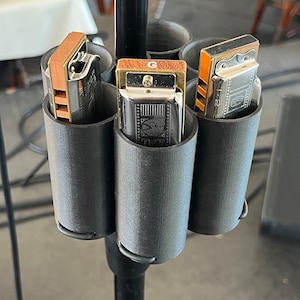 May include: A black metal stand with four black plastic holders for harmonicas. The harmonicas are silver and have a brown and gold design. The stand is attached to a microphone stand.