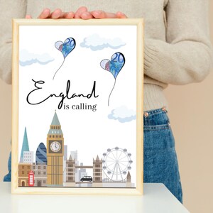 Peut inclure: Impression encadrée représentant l'horizon de Londres avec Big Ben, le London Eye et le Tower Bridge. Deux ballons en forme de cœur avec le chiffre 20 flottent au-dessus. L'inscription "England is calling" est en cursive.