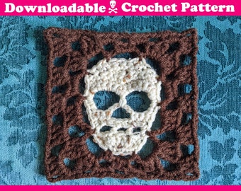 May include: A brown crochet square with a white crochet skull in the center. The skull has a detailed design with eye sockets, a nose, and a mouth.