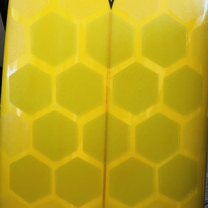 May include: Yellow surfboard with a honeycomb pattern and the text "22.9 Matt" on the bottom.