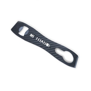 May include: Black carbon fiber bottle opener with the word "METHANOL" cut out of the metal.
