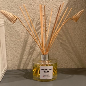 May include: A clear glass aromatherapy diffuser with wooden reeds and spiral accents. The label reads "Jamaica Me Crazy" and "FORIN LEE CO." The yellow liquid is contained in a 177 ml bottle.