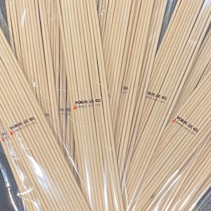 Puede incluir: Un conjunto de palitos difusores de madera marrón claro, empaquetados en plástico transparente. Los palitos están agrupados y el embalaje incluye el texto "POR/H CO. HANDMADE WITH LOVE."