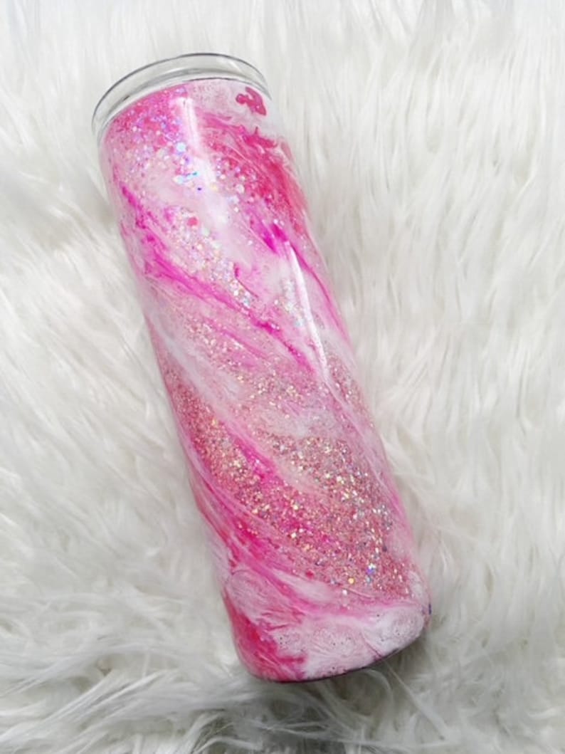 May include: A pink and white glitter tumbler with a swirl design.