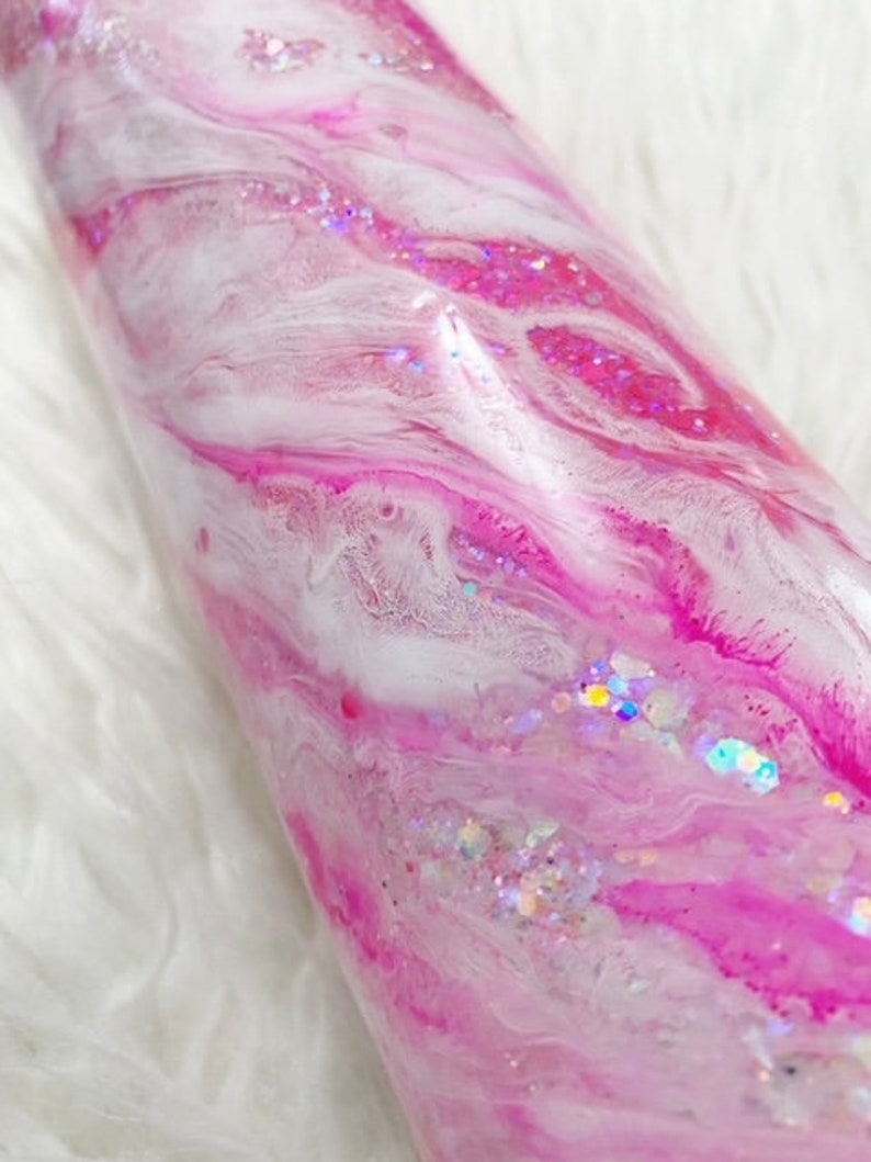 May include: A pink and white tumbler with a swirl design and iridescent glitter.