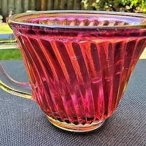 以下が含まれることがあります： 赤いガラス製のティーカップで、透明な取っ手とリブ模様が施されています