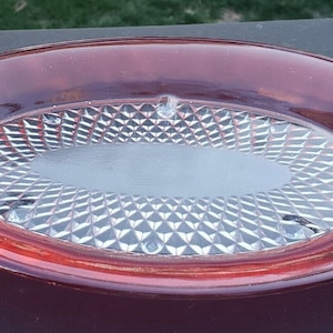 May include: A red glass serving dish with a clear, diamond-shaped pattern on the bottom.