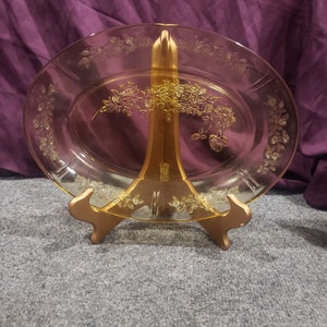 May include: A yellow glass serving platter with a floral design. The platter is on a wooden stand.