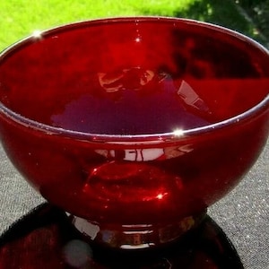 Op de afbeelding: Een diepe rode glazen kom met een voet. De kom is gemaakt van robijnrood glas en heeft een gladde, glanzende afwerking.