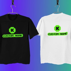 May include: Two t-shirts, one black and one white, with a green pixelated letter "K" and the text "CUSTOM NAME" printed on the front.