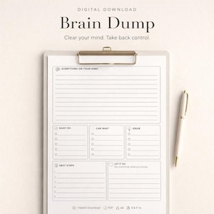 Può includere: Un portablocco bianco con clip dorata, con un design "Brain Dump". Il design include sezioni per "Everything on Your Mind", "Must Do", "Can Wait", "Ideas" e "Next Steps". Una penna bianca con dettagli dorati è appoggiata accanto al portablocco.