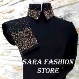 May include: Black long-sleeved shirt with a high collar and embellished with gold and silver sequins. The shirt has sequins on the collar, cuffs, and one shoulder. The shirt has the text "SARA FASHION STORE" printed on the front.