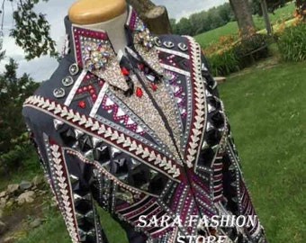 Op de afbeelding: Een zwart showjack met een geometrisch patroon en zilveren en rode versieringen. Het jack heeft een staande kraag en een ritssluiting. De tekst "SARA FASHION STORE" is zichtbaar op het jack.