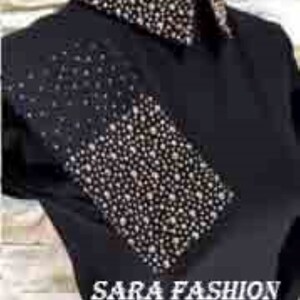 May include: Black shirt with a rhinestone design on the collar and a diagonal panel on the front. The shirt has the text "SARA FASHION STORE" printed on the front.