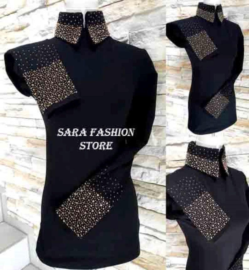 May include: Black long-sleeve shirt with gold rhinestone embellishments on the collar, cuffs, and shoulders. The shirt has a high collar and a fitted silhouette. The text "SARA FASHION STORE" is visible on the shirt.
