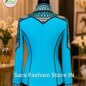 May include: A bright turquoise long-sleeve shirt featuring a high collar, black piping accents, and intricate geometric crystal embellishments across the shoulders, collar, and cuffs. The text Sara Fashion Store IN is printed at the bottom.
