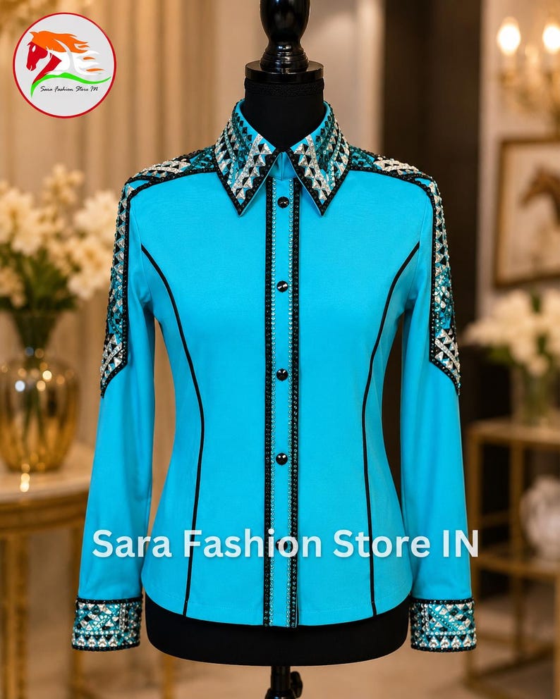 May include: A bright turquoise long-sleeve button-down shirt featuring black piping along the seams and a central placket. The collar, shoulders, and cuffs are heavily embellished with silver and black geometric crystal patterns. Sara Fashion Store IN.