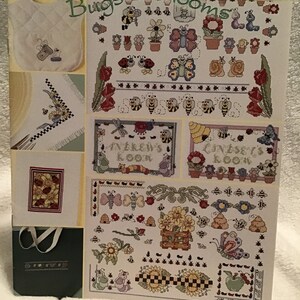 以下が含まれることがあります： 虫と花がカラフルに描かれた本の表紙。本のタイトルは「Bugs & Blooms」で、60種類以上の簡単なステッチデザインが掲載されています。