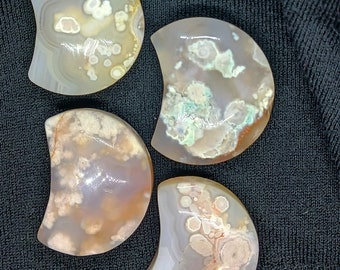May include: Four agate crescent moon shaped stones with a variety of brown, white, and green patterns.
