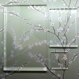 May include: A green background with a white floral pattern. Three clear glass frames are layered on top of the pattern. The frames are rectangular and have a subtle bevel.