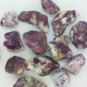 May include: A collection of tumbled pink and white stones with a speckled pattern. The stones are various sizes and shapes.