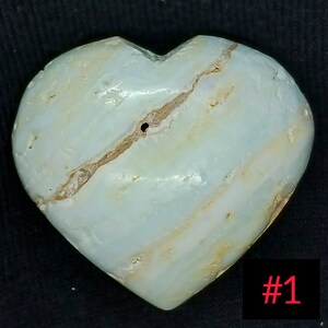 May include: A heart-shaped stone with a light blue and white striped pattern. A brown fissure runs across the stone. The number "1" is in red in the bottom right corner. The stone is likely a decorative item.