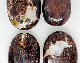 May include: Four polished, oval-shaped stones. The stones have a mix of colors, including deep brown, burgundy, white, and green. The stones have a smooth, glossy finish and are likely used for decorative or spiritual purposes.