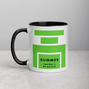 May include: White ceramic mug with a black rim and handle. The mug has a green graphic design with the text "SUMMER teacher's de parfum".