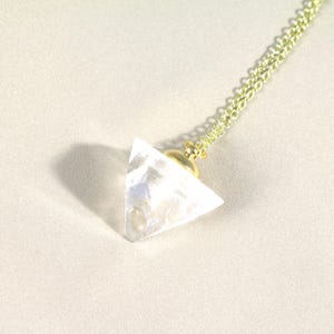 May include: A gold chain necklace with a clear crystal pyramid pendant.