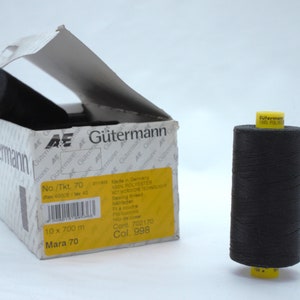 May include: A black spool of Gütermann Mara 70 thread with a yellow label. The spool is 700 metres long and is made of 100% polyester. The label also says "Made in Germany".