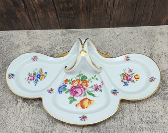 May include: A white porcelain serving dish with three sections and a gold handle. The dish is decorated with colorful floral designs.