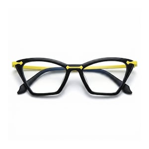 Puede incluir: Gafas de estilo ojo de gato con montura negra y un borde interior y detalle de puente en color amarillo brillante. Las lentes son claras y transparentes, integradas en un diseño de montura angular y afilado que resalta el contraste.