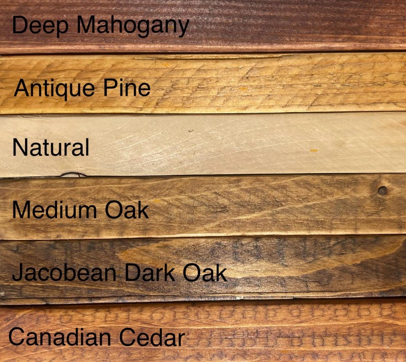 May include: Close-up of six wooden planks with different stain colors. The colors include Deep Mahogany, Antique Pine, Natural, Medium Oak, Jacobean Dark Oak, and Canadian Cedar. Each plank has the color name printed on it.