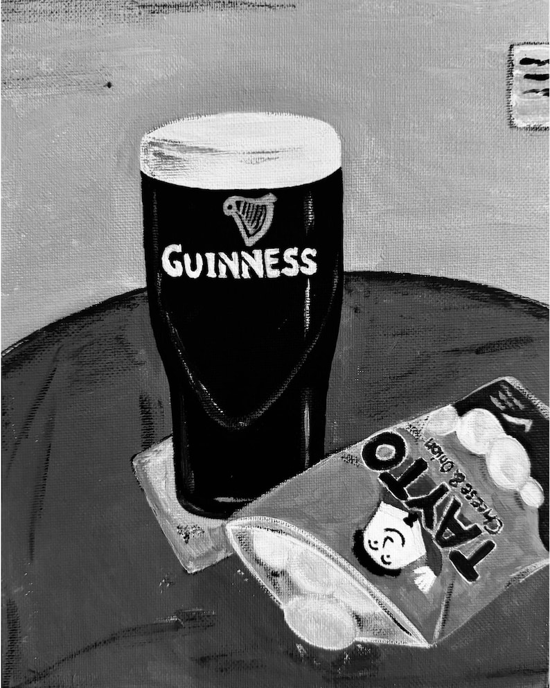 Peut inclure: Peinture en noir et blanc d'une pinte de Guinness avec le logo et le texte Guinness. &Agrave; c&ocirc;t&eacute; de la pinte se trouve un sachet de chips Tayto Cheese & Onion partiellement ouvert.