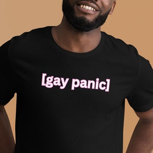 May include: A black t-shirt with the text "[gay panic]" printed in pink on the front.